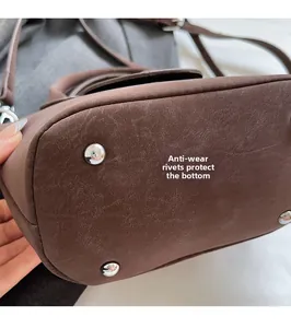 Detail view of deep brown leather handbag base with four anti-wear silver metal rivets