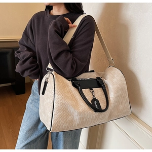 Close-up of beige woven texture travel bag with black leather trim and Heimish tag