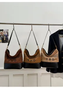 Detail of suede bucket bag showing YRO logo with black quilted leather bottom