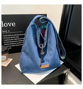Close-up of blue suede tote bag showing drawstrings and colorful plaid lining fabric