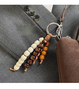 Close-up of a three-color beaded keychain charm accessory on a brown leather bag