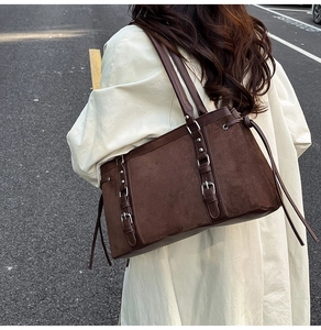 Detail view of large dark brown suede tote bag featuring sleek leather straps and buckles