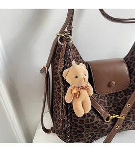 Detail of leopard print tote with brown leather flap and cute teddy bear charm