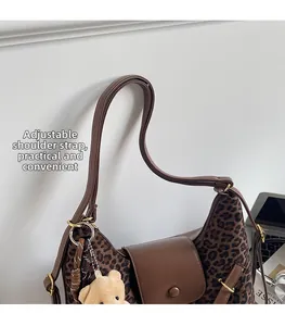 Detail view of leopard print tote bag with adjustable brown strap and plush bear charm