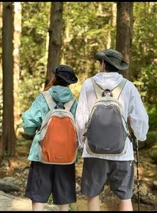 Outdoor hiking backpacks in contrast colors with multiple zipper pockets on forest background