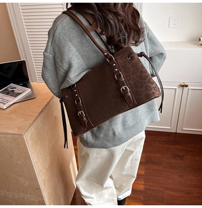 Detail of dark brown suede shoulder bag featuring leopard print accents and metal buckles