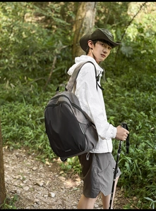 Detail of grey outdoor backpack with side compression straps against forest trail background