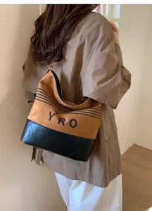 Detail of hobo bucket bag in tan suede and black quilted leather with YRO lettering