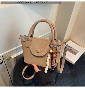 Detail of light khaki tote bag with textured faux leather and beaded charm accessory