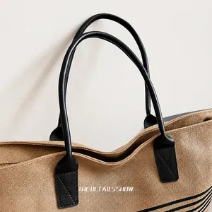 Detail showing the reinforced black leather handle and stitching of the canvas tote bag