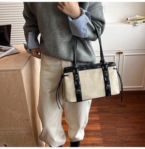 Detailed view of bicolor suede tote bag featuring black leather trim and metal buckles