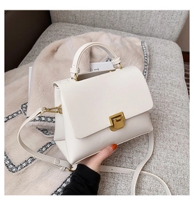 Detailed view of beige faux leather texture and vintage gold square buckle on handbag