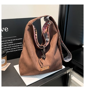 Detail of brown suede tote bag featuring ethnic floral lining and leather logo tag
