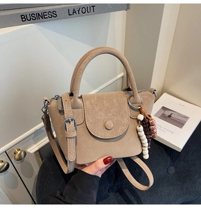 Detail of beige faux leather handbag with lychee texture and wooden bead charm