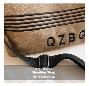 Detail of striped canvas tote with adjustable strap, metal buckle and QZBG embroidery