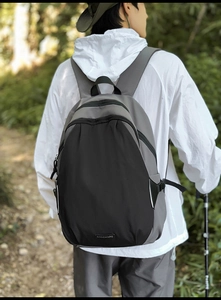 Outdoor color-block backpack worn on back in a scenic forest trail setting