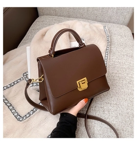Vue détaillée d'un sac bandoulière marron chocolat avec boucle dorée et texture cuir