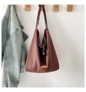 Detail of suede tote bag with knotted shoulder strap and floral lining accents