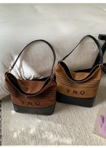 Detail of suede and quilted leather bucket bags in dark brown and light tan with gold hardware