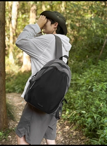 Detail of grey and black outdoor backpack with functional straps in a forest setting