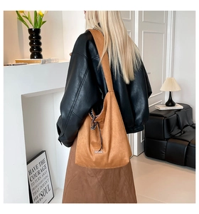 Detail of a large brown suede bucket bag featuring a drawstring closure and brand label