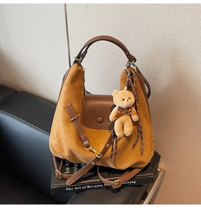Detail of suede patchwork tote bag with brown leather flap and cute plush bear charm