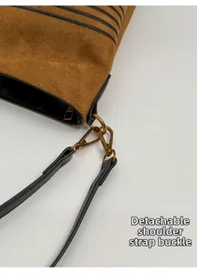 Detail of suede bucket bag featuring detachable shoulder strap and bronze metal lobster clasp