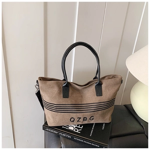 Detail view of brown canvas tote bag with black leather handles and QZBG lettering