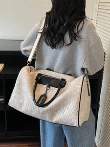Large cream woven travel bag with black leather handles and detachable strap on model