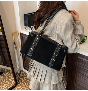 Detail of black faux suede tote bag with leather straps and silver metal buckles