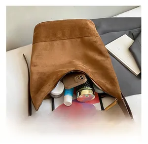 Macro shot of large capacity brown suede bucket bag interior holding a tablet and cosmetics