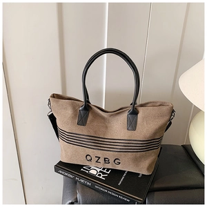 Detail of striped canvas tote bag with black handles and adjustable shoulder strap