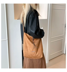 Detail of a large brown suede tote bag featuring a minimalist 'our fave' leather label