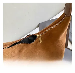 Close-up of golden zipper hardware and brown suede texture on the bucket bag