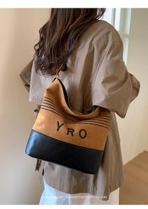 Detail of hobo bucket bag in brown suede and black quilted leather with YRO lettering