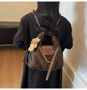 Detail of leopard print tote bag featuring a brown leather strap and a cute bear charm
