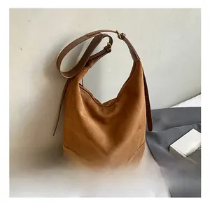 Detail of brown suede bucket bag with adjustable leather strap and gold hardware
