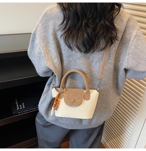 Detailed view of bicolor crossbody bag in beige and brown with decorative wood beads