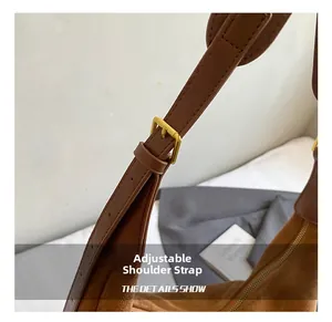 Close-up of golden adjustable strap buckle on a brown vintage suede shoulder bag
