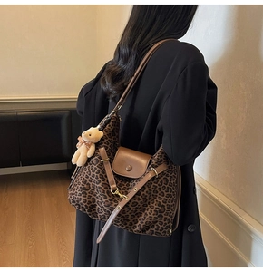 Detail of leopard print tote bag with brown leather trim and cute plush bear keychain