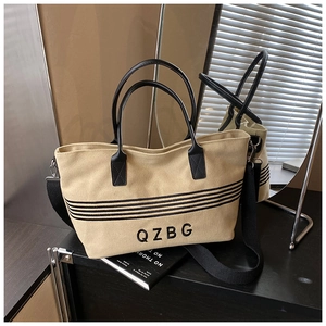 Detail of beige canvas tote with black stripes, leather handles and QZBG embroidery
