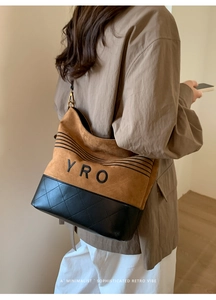 Detailed shot of a brown suede and black quilted leather tote bag worn over the shoulder