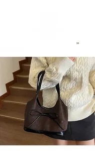 Detail view of retro brown bucket bag with a delicate black bow and contrast textures