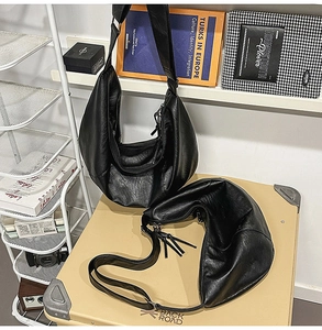 Détail du sac croissant en cuir plissé noir avec fermeture éclair et texture souple
