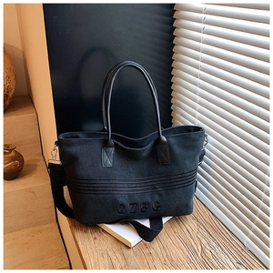 Detail of black striped canvas tote bag with QZBG embroidery on a wooden table