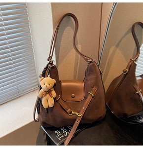 Detail of a large brown suede leopard-style tote bag with a cute teddy bear charm