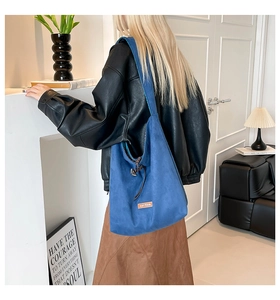 Detailed view of blue suede tote bag with leather drawstring and minimalist logo