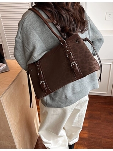 Brown suede tote bag with leopard print side panel and silver buckle straps worn by a model