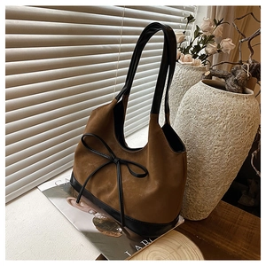 Detailed view of vintage brown suede bucket bag with black leather base and bow detail