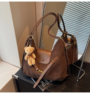 Detail of suede leopard print tote with plush bear charm and decorative scarf